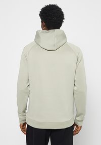 Szara bluza z kapturem, wykonana z gładkiego materiału z teksturowanym panelem na kapturze. Posiada rękawy raglanowe i dopasowany dół.