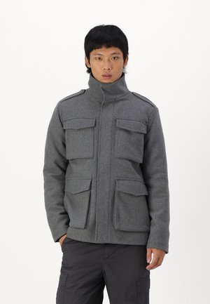 Chaqueta de mezcla de lana gris con cuello alto, que cuenta con cuatro bolsillos de solapa y hombreras. Diseñada para una silueta ajustada.