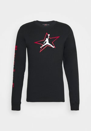 T-shirt noir à manches longues en coton avec un logo Jordan blanc à l'intérieur d'une étoile rouge sur la poitrine et du texte rouge sur la manche gauche.