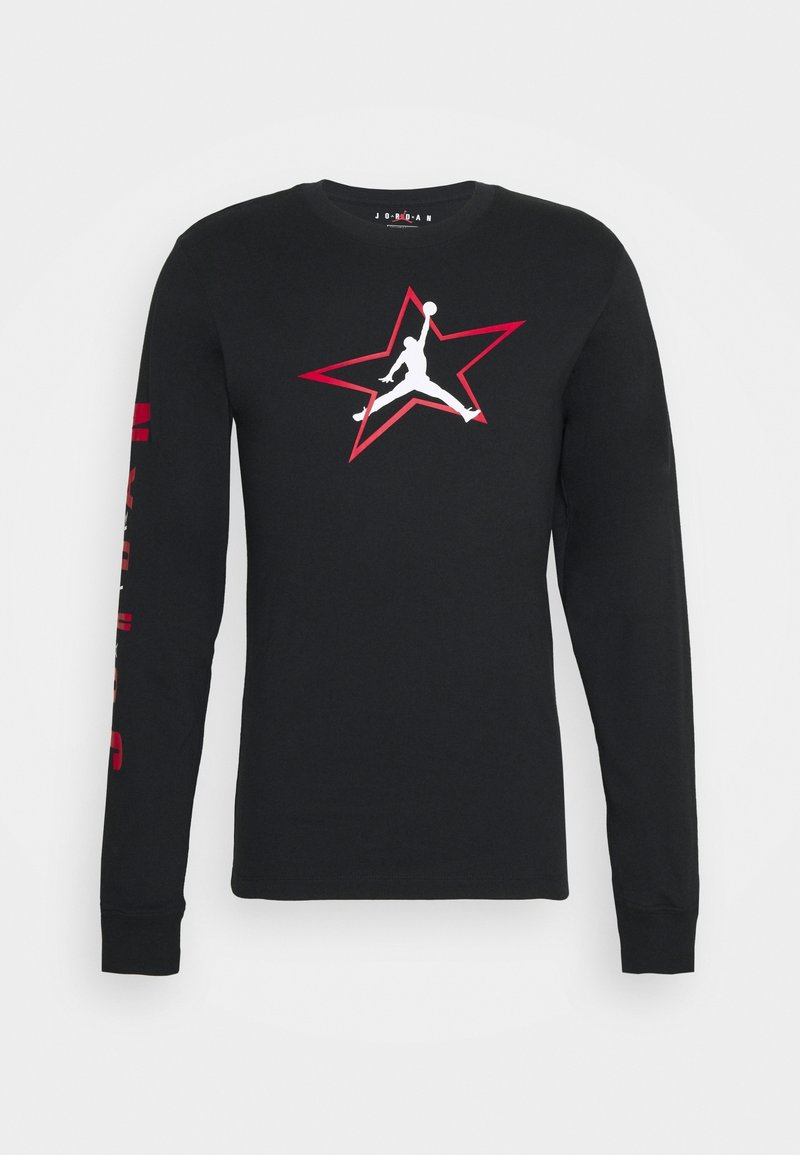 T-shirt noir à manches longues en coton avec un logo Jordan blanc à l'intérieur d'une étoile rouge sur la poitrine et du texte rouge sur la manche gauche.