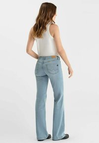 Jean flare bleu clair en denim, avec une taille mi-haute, des poches arrière avec des détails de couture et une patch en cuir sur la ceinture.