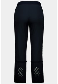 Černé sportovní kalhoty s vysokým pasem, které mají hladký povrch a reflexní vzory ve tvaru šípu na dolních otvorech nohou.
