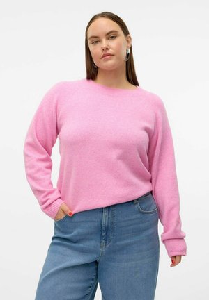 Pull en tricot rose à manches longues et col rond, associé à un jean en denim bleu clair. Le tissu semble doux avec une finition légèrement texturée.
