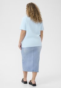 Lichtblauw T-shirt met korte mouwen, gecombineerd met een middellange jeansrok. Het shirt heeft een ontspannen pasvorm; de rok heeft een subtiele wassing en een achternaaddetail.