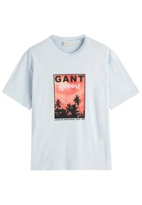Camiseta de algodón azul claro con un diseño enmarcado en negro que presenta "GANT Resort", palmeras y texto en rojo sobre un fondo degradado.