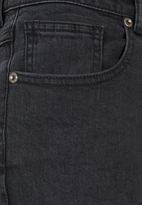 Los jeans de mezclilla oscura presentan un diseño clásico de cinco bolsillos, con un pequeño bolsillo delantero, remaches plateados y un acabado suave y texturizado.