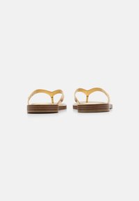 Brune treflip-flops med gule stropper, med et bølgemønster. Sålene ser flate ut med et lagdelt utseende og enkel finish.