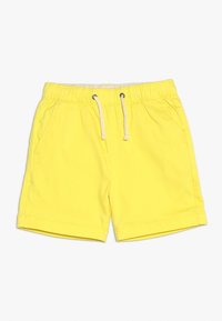 Žluté šortky vyrobené z lehkého materiálu, vybavené elastickým pasem se šnůrkou a bočními kapsami. Krátká délka nohavic s lemovaným okrajem.
