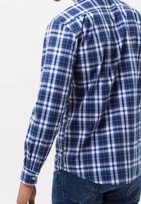 Modrá a bílá kostičkovaná košile s dlouhými rukávy, vyrobená z bavlny, s jedním manžetou a zakřiveným lemem vzadu.