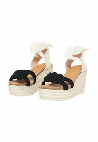 Sandali wedge espadrille neri con design annodato sulle cinghie, soletta beige e tacco intrecciato crema con lacci in tessuto alla caviglia.