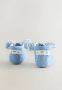 Pantofi pentru bebeluși din material albastru deschis, cu fundițe dungi, etichetă "fericit" și material texturat. Talpă moale și formă rotunjită.