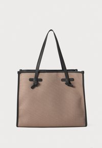 Beige tekstil tote-veske med svarte lærdetaljer og håndtak, med sløyfedetaljer på forsiden og en strukturert rektangulær form.
