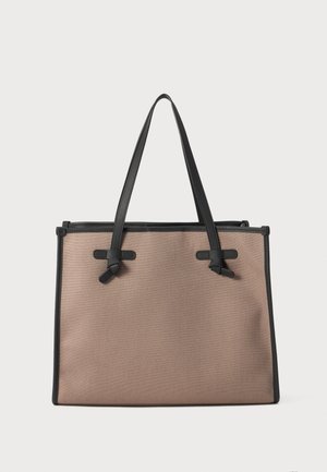 Beige Stofftasche mit schwarzen Lederelementen und -griffen, die vorne Schleifendetails aufweist und eine strukturierte rechteckige Form hat.