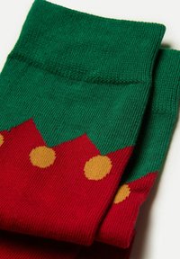 Rote und grüne Socken mit einem Zickzackmuster oben und gelben Punkten über den Körper. Hergestellt aus weichem, strukturiertem Material.