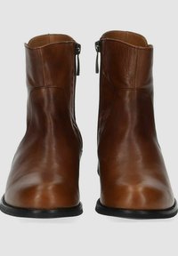 Stivali ankle in pelle marrone con una texture liscia, chiusura con zip e design a punta arrotondata; suola in gomma nera per maggiore durata.