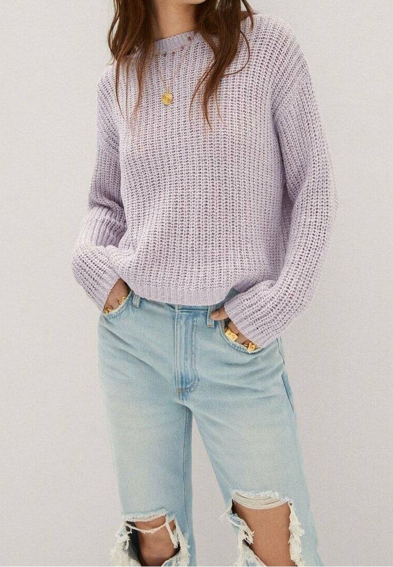 Vaalean kanelinlaventeri neulottu pusero teksturoidulla kuviolla, yhdistetty vaaleansinisiin kulutettuihin farkkuihin. Tiukka malli, jossa käännetyt hihat ja näkyvät kalvosimet.