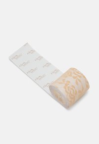 Valjak dekorativne ljepljive trake u svijetloj breskvaste boji s uzorkom čipke, glatke teksture i papirnate podloge s oznakama "magic".