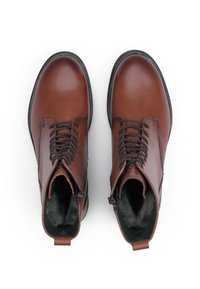 Bruine leren enkellaarsjes met een gladde afwerking, ronde neuzen en een vetersluiting aan de voorkant. Voorzien van een rits aan de zijkant en een zachte binnenvoering.