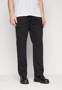 Svarta cargobyxor gjorda av robust tyg, med sidofickor, rak passform och subtila stygn detaljer. Bärs med svarta skor.