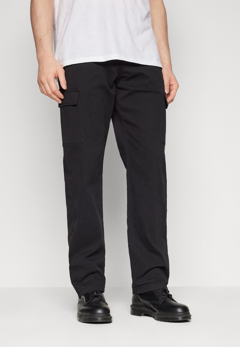 Svarta cargobyxor gjorda av robust tyg, med sidofickor, rak passform och subtila stygn detaljer. Bärs med svarta skor.