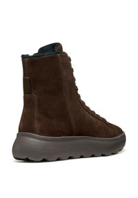 Stivaletto in suede marrone con design lacciato, colletto morbido e suola spessa in gomma imbottita. Presenta un dettaglio di cucitura tono su tono.