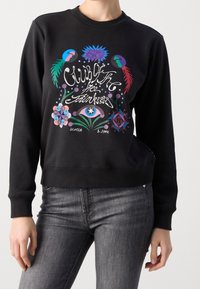 Sudadera negra con gráficos coloridos de loros y flores, cuello redondo, puños y dobladillo acanalados, fabricada con un tejido suave.