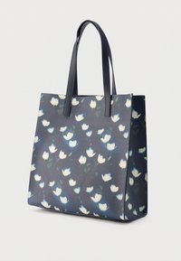 Sac fourre-tout bleu marine avec un motif floral blanc, texture lisse, deux anses solides, et un design structuré avec ouverture supérieure.