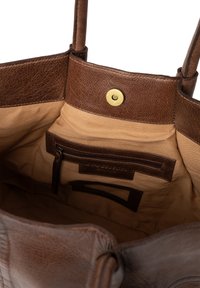 Brązowa skórzana torba tote z teksturowanym wykończeniem, z beżową tkaniną wewnątrz, mosiężnym zapięciem na nap oraz kieszeniami wewnętrznymi do organizacji.