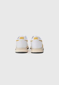Pair of white and yellow Asics sneakers shown from the back on a plain light background.