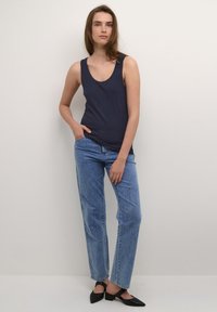 Jūrų mėlynos juostos tankų viršus derinamas su šviesiai mėlynomis aukštu liemeniu džinsų kelnių ir juodais smailiais slingback batais. Lygus audinys; laisvas fasonas.