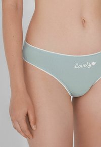 Hellblaue Baumwollunterwäsche mit weißer Spitzenkante und gesticktem "Lovely"-Text, mit glatter Textur und moderatem Schnittdesign.