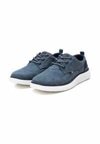 Zapatos de lona azules con cordones, acabado texturizado, suela de goma blanca y acentos en negro contrastante en el talón y la parte posterior.