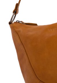 Braune Lederhandtasche mit einer weichen, strukturierten Oberfläche. Verfügt über eine geschwungene Form, metallische Hardware und ein geprägtes Markenlogo.