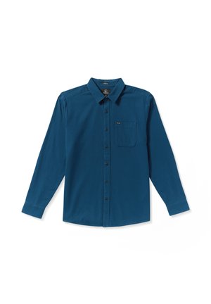 Chemise à manches longues de couleur bleu profond, en tissu lisse. Présente un devant à boutons, un col pointu et une poche poitrine unique. Boutons noirs.