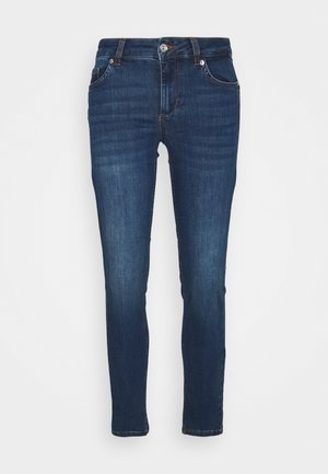 Mørkeblå slim-fit denimjeans med frontlommer, bæltestropper og lukning med knap mod en hvid baggrund.