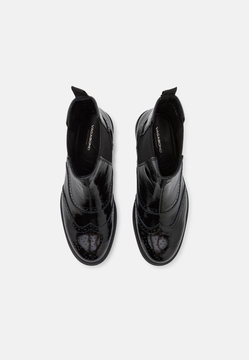 Bottines Chelsea en cuir noir avec une finition brillante, des perforations décoratives et des panneaux élastiques sur les côtés. Semelles en caoutchouc plates.