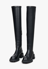Black knee-high leather boots with a chunky sole, reinforced stitching, and a side zipper detail for easy wear. Smooth texture throughout.