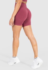 Bordeaux hoge taille shorts met een nauwsluitende pasvorm, gemaakt van rekbaar materiaal. Heeft een nette zoom en is te combineren met witte sneakers.