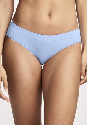 Frau trägt hellblaue nahtlose Slips, gezeigt von der Taille bis zur Mitte des Oberschenkels vor weißem Hintergrund.