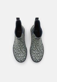 Botas de tobillo estampadas con un diseño de margaritas en blanco y negro, parte superior de tela texturizada, punta redondeada y paneles laterales elásticos para facilitar su uso.