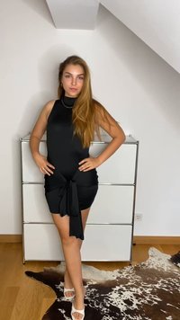 Μαύρο αμάνικο φόρεμα με εφαρμοστό κορσέ και κόμπο στη μέση. Φοριέται με λευκά πέδιλα, πάνω σε ένα καφέ ταπήλι από αγελάδι.