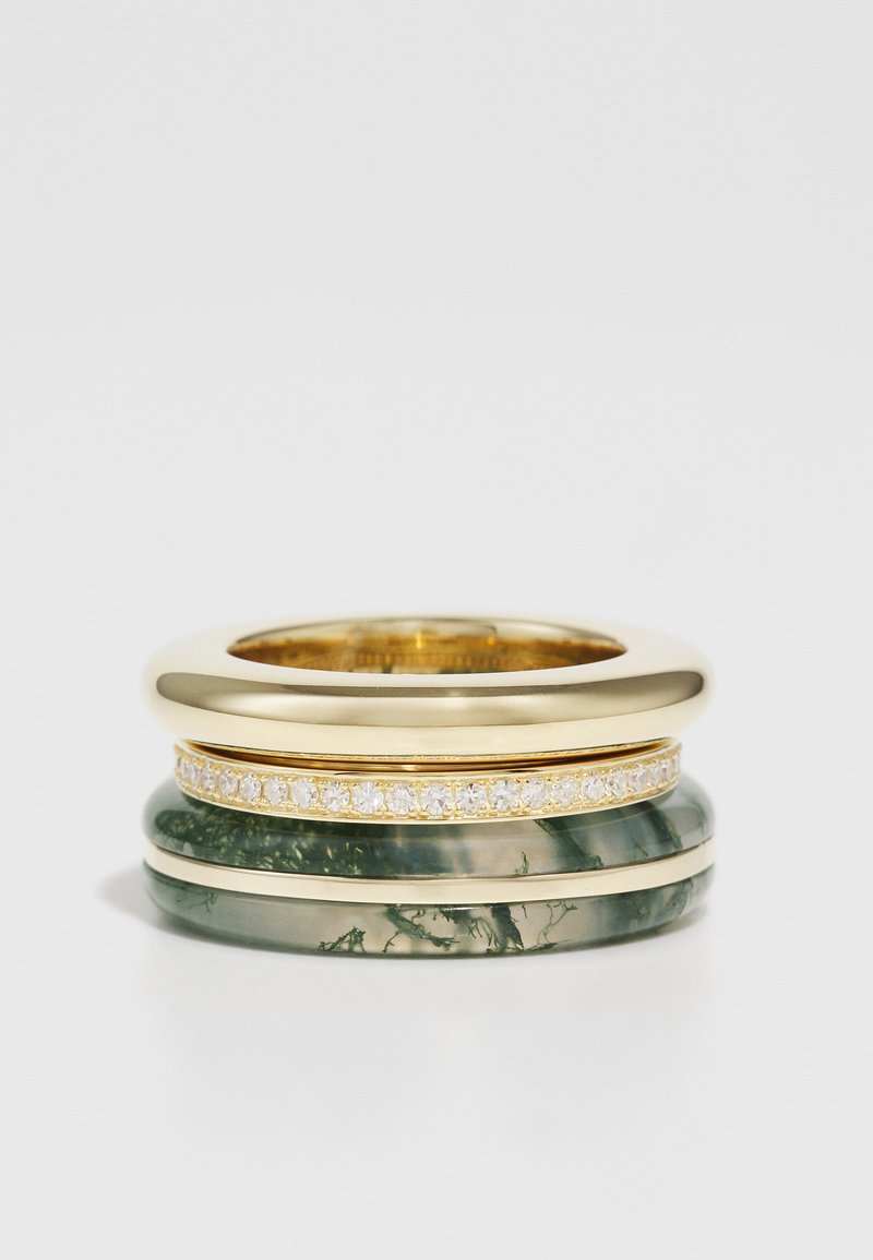 Három egymásra rakott gyűrű: egy sima arany gyűrű, egy zöld márványos kőgyűrű finom arany díszekkel, és egy átlátszó kőgyűrű apró gyémántokkal.