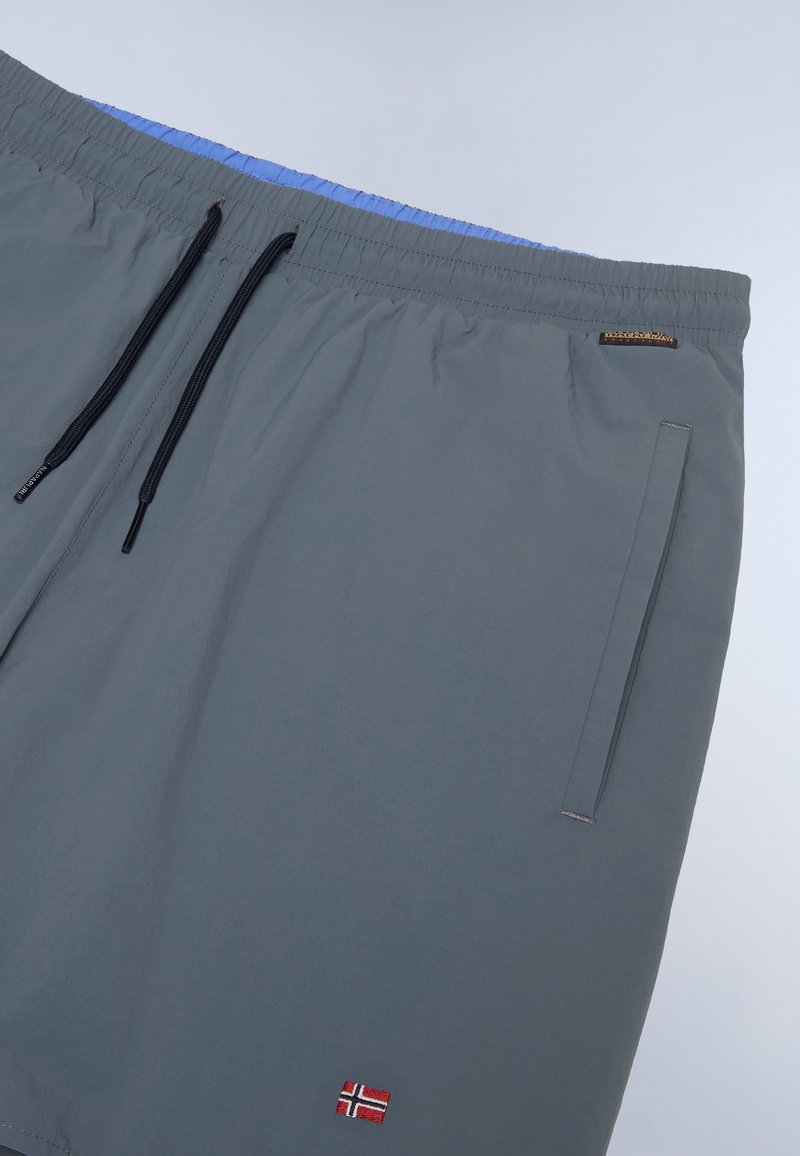 Shorts de bain gris avec une taille élastique, doublure intérieure bleue, cordon de serrage, deux poches latérales et un petit détail de drapeau brodé.
