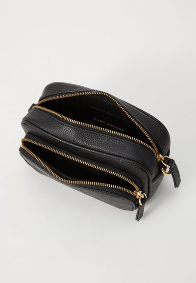 Sort læder crossbody taske med to lynlåslommer, guldfarvet hardware, pebble tekstur og mærkenavn synligt indeni tasken.