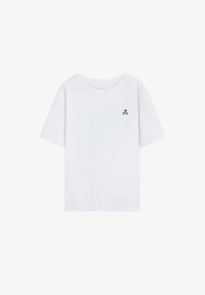 Niño con cabello rubio que lleva una chaqueta verde claro, camiseta blanca, pantalones verde claro y zapatillas blancas, de pie con una mano en el bolsillo.