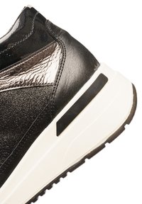 Schwarzer Sneaker mit glänzenden und strukturierten Abschnitten, einer weißen Zwischensohle und einem schwarzen Akzent an der Ferse. Entworfen für Unterstützung und Komfort.