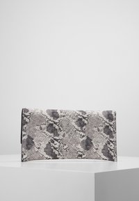 Porte-monnaie en forme de pochette à motif serpent noir et blanc. Texture lisse avec une forme rectangulaire, présentant un design à rabat et sans matériel visible.