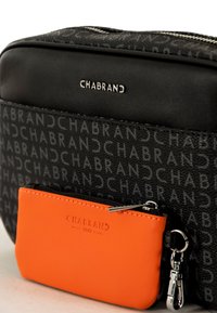 Bolsa negra con diseño de logo en relieve, con cremallera y acabado texturizado. Incluye un pequeño monedero naranja con cremallera adjunto.