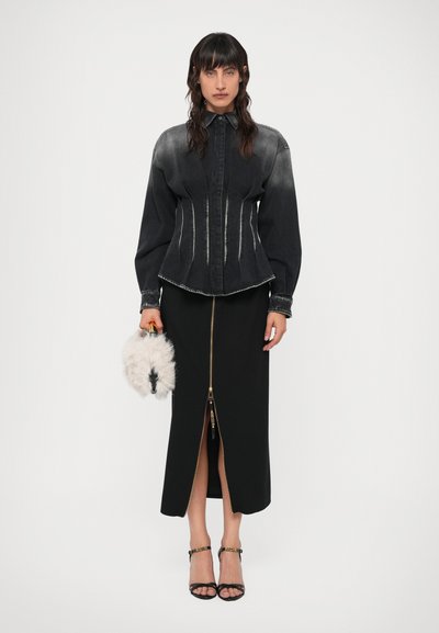 Juodas džinsinis švarkas su prigludusia juosmens dalimi, išblukusiu vaizdu ir baltais siūlais; derinamas su juoda sijonu, turinčiu priekį užtrauktuką ir plyšį.