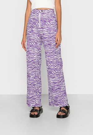 Calças largas de padrão zebra em roxo e branco com cintura alta, apresentando um fecho na frente e dois bolsos laterais, feitas de tecido leve.
